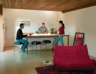 Thanks to a skylight and the absence of conventional wall cabinets, the kitchen looks more like an airy extension of the living room than a dedicated space for cooking. With the sink, oven, and storage tucked behind and a long countertop in front, the island serves as a more versatile built-in feature.