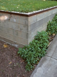 Concrete retaining walls form an outdoor terrace that serves as a dining area, conference room, and workshop. The three-quarter-inch construction gravel from George L. Throop Company allows rain to percolate into the ground and irrigate a lemon tree rather than create polluting runoff.