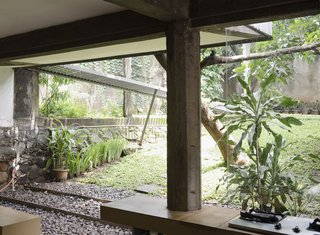 Not only does the open kitchen permit breezes in under the second floor, it encourages the kids to race outside to play. A large yard and lush foliage make for an inside-outside living dream.