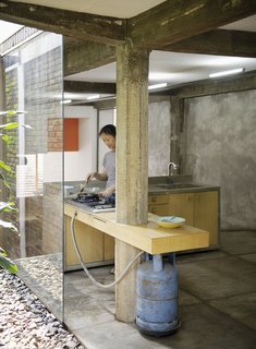 Here Sundari puts a bit of food together in the kitchen. A gas-fired grill and concrete countertop give the place a rough-hewn feel, and certainly evokes architect Ahmad Juhara's rally cray, "Ad hocism is my religion."