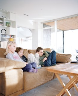 Axel, Anna, and a friend watch television in the living room.