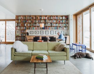 The First LEED for Homes–Rated House in Utah - Photo 2 of 10 - Sparano works in the dining area, where books about travel, architecture, and food, as well as framed architectural drawings from his grad school days, line the back wall. The hollow glass-walled light fixture is from Ikea; every few months, the family fills it with a different season-inspired item, such as pinecones in the fall and feathers in the winter, as pictured here.