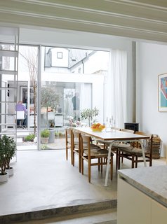 The view from the kitchen is as lively as it is light, taking in the dining area, tiny courtyard garden, and the separate office building backed by the jumble of old buildings to the rear. The rustic dining chairs are by Börge Mogensen from Karl Andersson & Söner.
