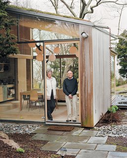 Large sliding windows retract at the corner, opening the living area onto a lawn overlooking Long Island Sound.