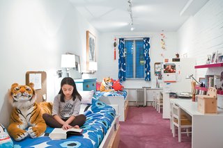 The girls’ narrow bedroom gets natural light from a single window. White paint and furniture (accented with Marimekko print linens) keep the space feeling bright.