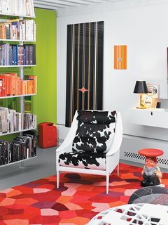 Dine painted all the walls, the ceiling, and the ceiling joists white to maximize the feeling of lightness in the apartment. In addition to encouraging a general glow, the bright white walls make the green cabinets and the one wall clad in Clarence House wallpaper appear all the more dramatic. The Vitsœ shelving system designed by Dieter Rams, which separates the playroom/office from the living room, holds a rainbow of books but is open enough to let natural light filter through.
