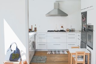 The kitchen maintains the white hue of the house, and the couple finished its custom cabinetry in a glossy thermofoil to emphasize its utility as part of the central core.