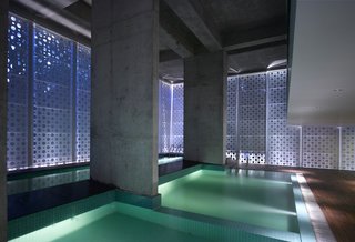 A Modern Aesthetic in Mumbai - Photo 13 of 17 - An interplay of geometries in what Khanna calls "the belly of the building." Uplights create new angles of light, raw concrete retains a rough edge and square pool tiles add texture and color while offsetting the perforated circles. The dropped ceiling at right is part of a small balcony overlooking the pools; beneath it is a sitting area.