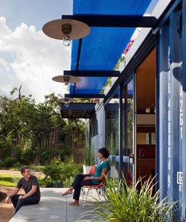 Friends of both the resident and the architect post up on the porch. Poteet attached beams to the container and topped them with a Polygal sheet for shade. The lamps were custom made by the architect from recycled tractor parts fitted with vapor lamps.