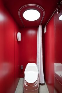 Maximizing space was of utmost importance in the 8-by-4-foot bathroom, which consists of an open shower in front of an electric composting toilet by Sun-Mar. Poteet and Hill chose a red sheet metal for the walls and laid down a non-slip epoxy flooring.