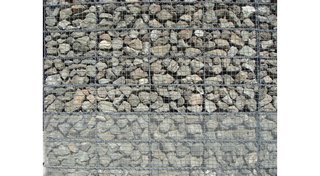 The exterior walls of the structure are industrial wire cages filled with locally sourced basalt.