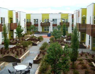 The large rooftop courtyard is filled with lush greenery, a jungle gym, picnic tables and benches.
