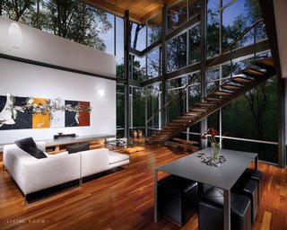 The entrance progresses from the top of the hill, across a bridge and into a balcony foyer. There the forest fills the interior through north-facing glass walls. A stair descends past the glass to the main living floor, which opens onto a partially secluded south-facing terrace below the bridge.