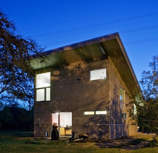 The rear of the concrete-clad house leads to the small kitchen, off of which Wong parks his scooter (he and his family rarely drive their car; they typically bike or walk around the neighborhood). The large planter from Big Red Sun serves as a focal point for the main axis, which runs straight through the middle of the house. Upstairs is the sleeping loft. The home uses cellulose insulation, made from recycled newspapers and other paper sources.