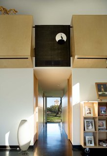 A view along the main axis through the house and into the backyard, with the campanile of a nearby church beyond. "The architects worked to situate the house to take advantage of this view," notes Wong. On either side of the main hall is Wong’s office, storage and a bathroom, with the kitchen at the end. Above, the patinaed steel balustrade hides a vent and incorporates a sculpture Wong’s parents brought back from a trip to China. "They brought it back right when Jay was designing the panel, and it just fit," says Wong. "It depicts a crane and a tortoise, traditional Chinese symbols of long life." As the sun hits the cutout and sculpture through the day, it creates a play of light and shadows.