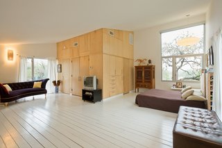 The open sleeping loft. Wong recently added a simple wall at left to create an enclosed sleeping area for Jasmine. He also built the headboard, which doubles as storage space for the large rolls of paper he uses as backdrops for photo shoots. Wong wanted a light floor; the architects whitewashed the tongue-and-groove subfloor decking, which helps bring in even more light from the dominant, East-facing window. George Nelson lamp.