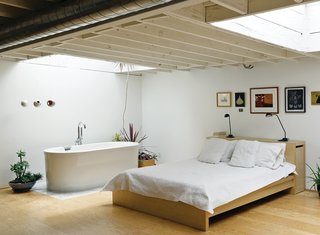 The bedroom mixes a bed and lamps from Ikea with a deep, luxurious bathtub (an inexpensive model from Neptune). The artworks include original prints by New York artist Franco Mondini-Ruiz.