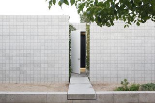 The front door is accessed by a 'floating' concrete bridge that bisects the two wings of the house.