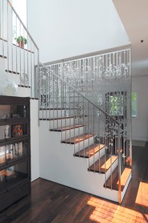 In a renovation of an existing farmhouse, a hanging screen composed of aluminum circles and lines, cut with a CNC water jet, separates the entry from the staircase and rear kitchen area.