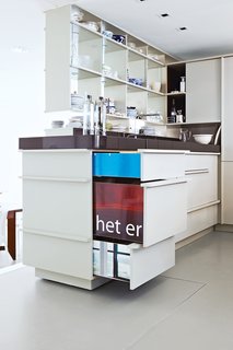 This Home Takes Recycling to the Next Level - Photo 12 of 13 - The cabinetry in the kitchen and elsewhere is crafted from discarded, chopped-up billboards. White paint camouflages their fronts, but when pulled open, their colorful sides offer a glimpse of their previous life as streetside advertising.