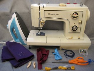 Here are the materials you need to make it happen:<br><br>-iron<br><br>-sewing machine<br><br>-straight pins<br><br>-scissors<br><br>-approximately 1/4 yard faux suede cord (it's the blue one there)<br><br>-embroidery thread<br><br>-measuring tape<br><br>-approximately 1/4 yard twill tape (or any kind of tie for the top, really: hemp or cotton cord, a few strands of ric-rac, whatever you like)<br><br>-two buttons<br><br>-1/3 yard fabric. Lots of types will work, but I chose a mid-weight cotton twill (a previous sling in linen was a little light)<br><br>-needle<br><br>-safety pin (the bigger/sturdier the better)