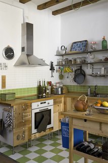 The kitchen cupboards were crafted from recycled wooden wine boxes, and the countertop is untreated wood certified by the Forest Stewardship Council (FSC) from Ikea. The green-and-white tiles are from a local company, TAU Cerámica.