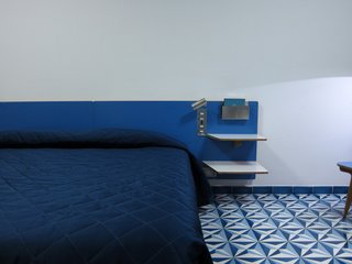 The 96 rooms face either the park or the ocean, and they are all outfitted with nearly identical furnishings, including these custom-designed headboards covered in blue laminate. Buttons to the side operate the mechanical louvers and bedside lights.