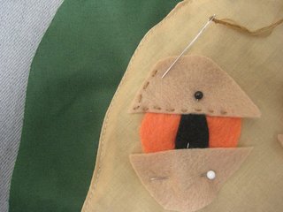 Pin his features into place, then hand-stitch them on, matching the embroidery floss to the feature.