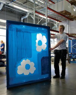 Next, the textile printing machine is readied. Here, Jan Möller takes a ready screen for the iconic Unikko fabric to be placed on the machine.