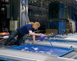 The printing machine moves fabric forward automatically, even though workers spread the inks across the plates by hand. No computers are needed to determine the right quantity.