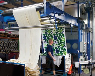 After printing, the fabric is transferred to the steaming machine, where steam heated to 219 degrees Fahrenheit fastens the color to the fabric, ensuring durability and brightness. Next, the textiles go through washing in 203-degree water to shrink them down to their final sizes. A finishing machine applies any additional treatments, like softener, to the washed fabric. Here, the colors of Katsuji Wakisaka’s Green Green fabric are fastened to the cloth.