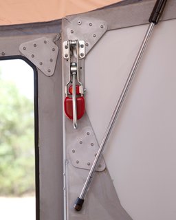 Hooks on the inside (like the mechanism with the red tab) latch into the camper's roof to help hold it down. Throughout the camper, small cricket images are laser-cut into the aluminum frame. The camper's name hints at its shape and is meant to conjure visions of sleeping under the stars with crickets chirping nearby.