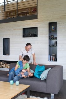 The open-plan living room and kitchen are a giant playground for five-year-old Suresh and his parents, as is the durable sofa and table base from Room & Board. Steel alcoves inset into the white-stained cedar wall shelter firewood, books, and treasured objects.