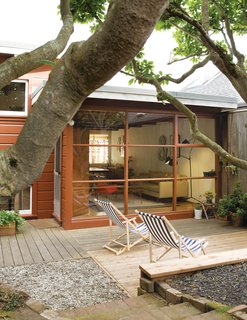 A pair of deck chairs from the Conran Shop brighten up a deck designed and built by Mark Congdon Landscape. Visible through the window are a Praying Mantis floor lamp from White Furniture and a fiberglass rocking chair from Modernica.