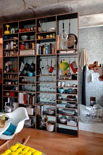 A Little Apartment Gets a Solid Renovation - Photo 4 of 8 - Kordík uses his cabinet system to store far more than just dishes. Food, kitchen appliances, and books also hold court in the dining area. We love that the three volumes of Julius Shulman: Modernism Rediscovered live right beneath jars of snacks.