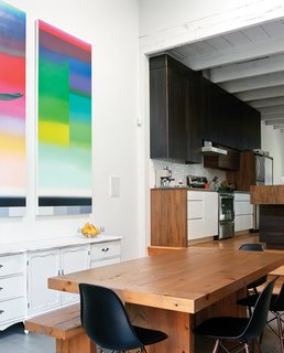 The architect designed the kitchen cabinetry, and used wood left over from the demo of the house’s exterior wall for the dining table. A piece by Nicolas Grenier hangs above a cabinet the residents found at a garage sale.