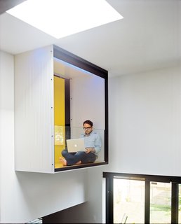 Raymond takes a break on the master bedroom’s interior balcony, which is cantilevered over the dining area.