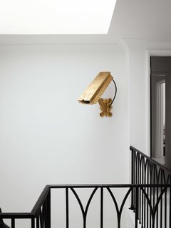 The gold (nonfunctioning) surveillance camera by artist Camp Bosworth in the stairwell previously hung in the glass entryway of the family’s former house in Houston.