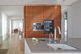 A Renovated Modernist Oasis in the French Riviera - Photo 5 of 9 - The kitchen features Miele and Bosch appliances surrounded by oak flooring from Bois Ditton; the shelves are walnut.