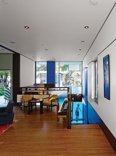In the living room, a vintage table and chairs by Edward Wormley sit in front of a Florence Knoll wall unit with a vintage jewelry chest by George Nelson for Herman Miller. The Hinaki pendant light over the stairs is by David Trubridge.