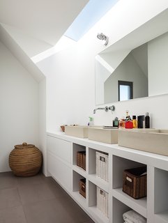 A Modern Take on the Pitched-Roof - Photo 11 of 12 - Similar architectural geometries are at play in the ceiling of a bathroom, where custom sinks by Concr3te accompany Grohe fixtures.