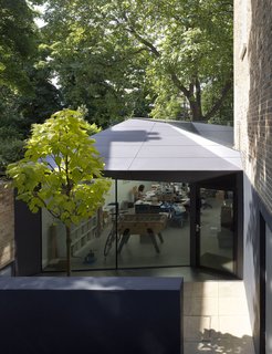 Victorian Home in London Gets a Modern Office Addition - Photo 2 of 7 - Backyard excavation created a sunken courtyard, where the side entrance to a new 750-square-foot office space lies. The exterior is clad in Corian, a surface normally found on countertops. "The clients love that they can go to another wing of the house and have an office," says Brooks. "There's a physical seperation. We’ve designed it so in the future, if they close the firm, they can open up the door between the office and the dining room and connect the entire basement floor."