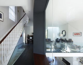 Victorian Home in London Gets a Modern Office Addition - Photo 7 of 7 - On the mezzanine level, different styles and eras complement each other, from the Georgian staircase to the sheets of glass and the Lola Convex Mirror to the James Irvine sofa.