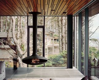 A wood-burning stove by Euroflues is suspended from the ceiling in the living room. The glass curtain-wall system that surrounds it was a year in the making. It was painstakingly designed and tested so it would hold up to punishing winds off the Pacific Ocean that can reach 120 mph.