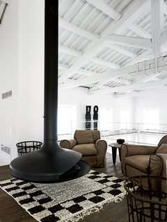 In the upper-level seating area, an Ergofocus fireplace is flanked by a pair of leather armchairs designed by Navone for Baxter
