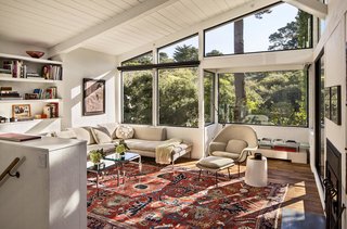 Bright Renovation of a 1970s Big Sur Home - Photo 4 of 10 - Schicketanz whitewashed the living room’s wood walls and replaced the carpet with teak flooring reclaimed from elsewhere on site. Workers also dismantled the dark stone fireplace to widen the view, installing an efficient, compact fireplace on the southern wall. "From sunrise to sundown, you have light in the house," Schicketanz says. "It’s bright even on gloomy days."
