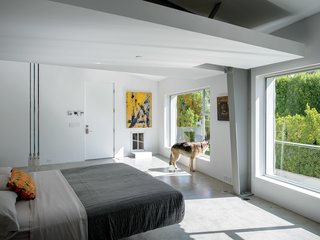 6 Ways to Declutter and Free Up Space in Your Bedroom - Photo 7 of 8 - In the master bedroom, a Droog Milk Bottle lamp hangs next to a Fluttua Bed designed by Daniele Lago. An artwork by Brooke Westlund hangs over a custom pet door for the client’s dog, Kona.