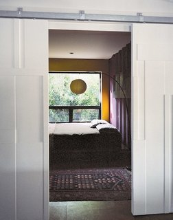 Though many of the interior surfaces have been spray-foam insulated and covered in Sheetrock, the couple, drawn to the natural patina of the shipping containers, opted to keep select areas of the material exposed. Closed off by bas-relief doors designed by Mathesius, the main guest room is one of few spaces that put whole walls of the raw surface on display, painted in Benjamin Moore’s warm Kalamata and Wasabi hues. benjaminmoore.com