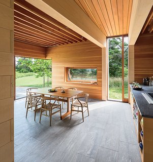Douglas fir and Alaskan cedar richly line the interior walls, and the flooring is made of Vermont slate. In the kitchen and dining area, a group of Wishbone chairs by Hans Wegner for Carl Hansen & Søn surrounds a table by local furniture maker Larry Hepler.
