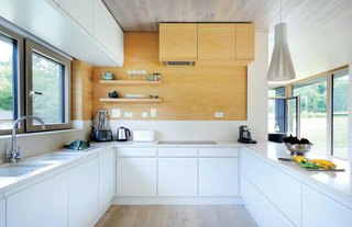 Bright interior finishes, including whitened oak on the floor and ceiling and Kitchen Collection’s Malmo cabinets in porcelain and oak colorways, were installed off-site.